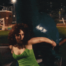 a woman in a green dress is sitting on the ground with her mouth open