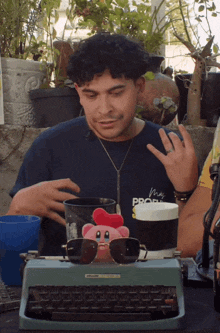 a man wearing a shirt that says " my profi " sits at a typewriter