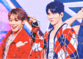 a man in a red jacket is pointing at another man in a plaid cardigan