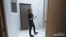 a woman in a black shirt and black pants is standing in a hallway .
