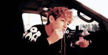 a young man is blowing soap bubbles in a car while wearing a black shirt .