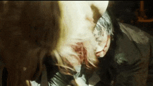 a man and a woman are standing next to each other in a dark room . the woman has blood on her face .