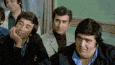 a group of men are sitting in a classroom and one of them is smiling