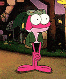 a cartoon frog wearing a green hat and goggles is standing on the grass .