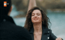a woman in a black leather jacket is smiling and looking at a man in a black jacket