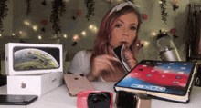 a woman with pink hair is sitting at a table surrounded by apple products