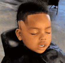 a young boy is sitting in a chair with his eyes closed