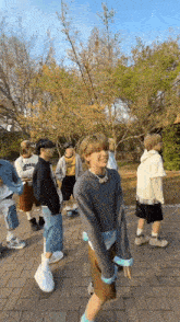 a group of people are standing on a brick sidewalk .