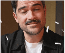a man with a beard and mustache is making a funny face with confetti falling around him