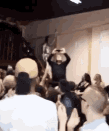 a crowd of people are gathered in a room and a man is taking a picture of a woman .