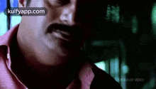 a close up of a man 's face with a mustache and a red shirt .