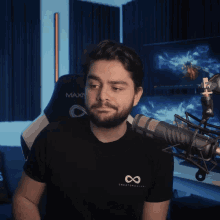 a man with a beard wearing a black shirt that says infinity on the back