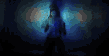 a woman is sitting in a dark room with a blue light behind her .