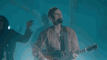a man playing a guitar in front of a crowd with their hands in the air