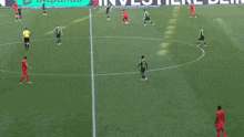 a group of soccer players are playing on a field with a sign in the background that says investe