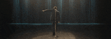 a man is standing on a stage with his arms outstretched in front of a row of lights