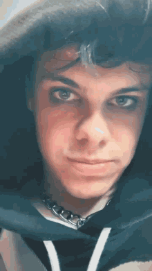 a close up of a young man 's face wearing a necklace