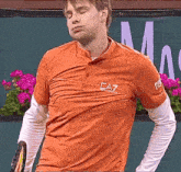 a man wearing an orange shirt that says ea7 on the front