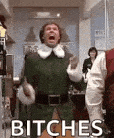 a man in a green elf costume is screaming in a room with the words `` bitches '' .