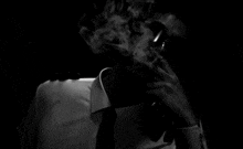a man smoking a cigarette in a dark room