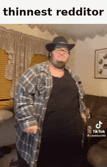 a man wearing a plaid shirt and a cowboy hat is standing in a living room with the caption " thinnest redditor "
