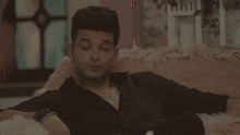 a man in a black shirt is sitting on a pink couch