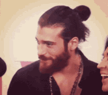 a man with a beard and a bun is standing next to a woman and smiling .