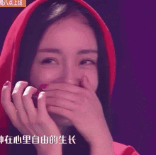 a woman wearing a red hoodie covering her mouth