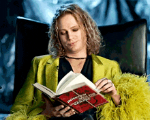 a woman in a yellow jacket is reading a book called interview with the vampire