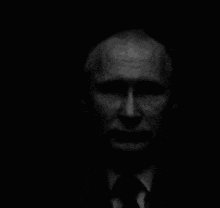 a black and white photo of a man 's face in a suit and tie .