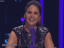a woman sitting in front of a microphone with the hashtag lialmeida05 on the bottom