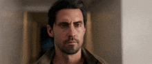 a man with a beard is looking at the camera .