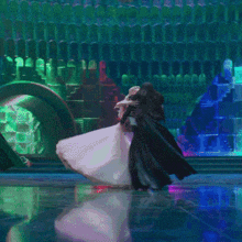 a woman in a white dress and a man in a black cape dance on a stage