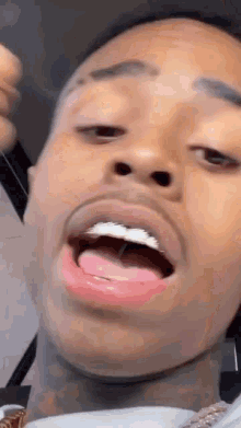 a close up of a man 's face with his mouth open and his tongue hanging out .