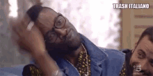 a man with glasses and a bandage on his head is laying on a couch .