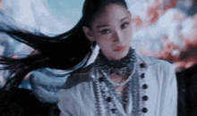 a woman with long black hair wearing a white shirt and necklace