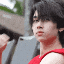 a close up of a person 's face with a red tank top on