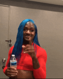 a man with blue hair is holding a bottle of water