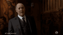 a man in a suit and tie is standing in front of a painting with the hashtag #theblacklist on the bottom