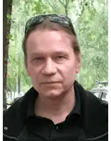 a man wearing sunglasses and a black jacket is looking at the camera