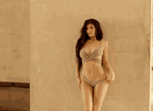 a woman in a bikini stands against a wall