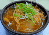 a bowl of soup with noodles and onions on top