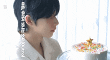 a man in a white shirt looks at a cake with sprinkles on it