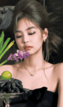 a woman in a black dress is holding purple flowers