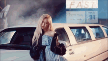 a woman is standing next to a white limousine in front of a fast food restaurant .