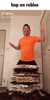 a man in an orange shirt is standing on a pile of wood and says hop on roblox