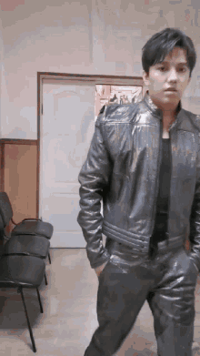 a man wearing a leather jacket and pants is standing in a room