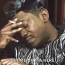 a man covering his face with his hand while smoking a cigarette and says get me outta here .