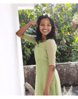 a woman in a green dress stands in front of a white wall