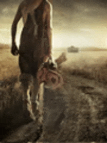 a woman is walking down a dirt road with a chainsaw .